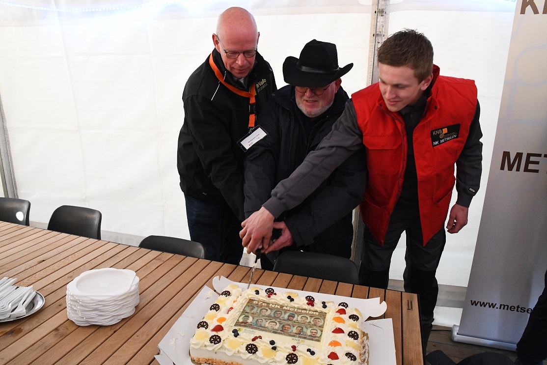 Piet Koppelaar (ReVaBo Oosterbeek), Jo Bogers (Jury-voorzitter) en finalist Tim de Bruin snijden de taart aan bij opening finale NK Metselen 2019